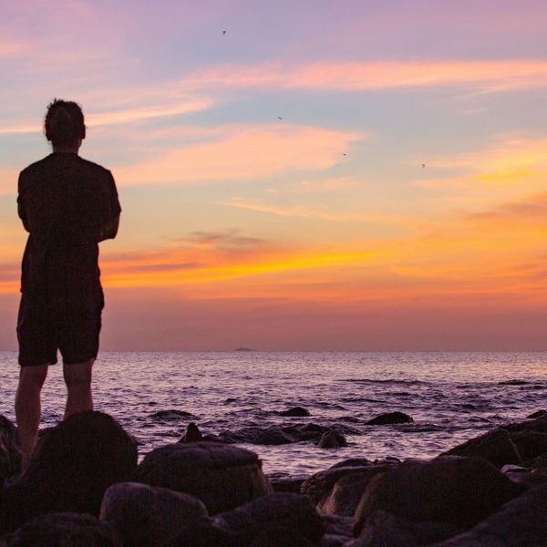 Silhouette of a person meditating against a pink circle.